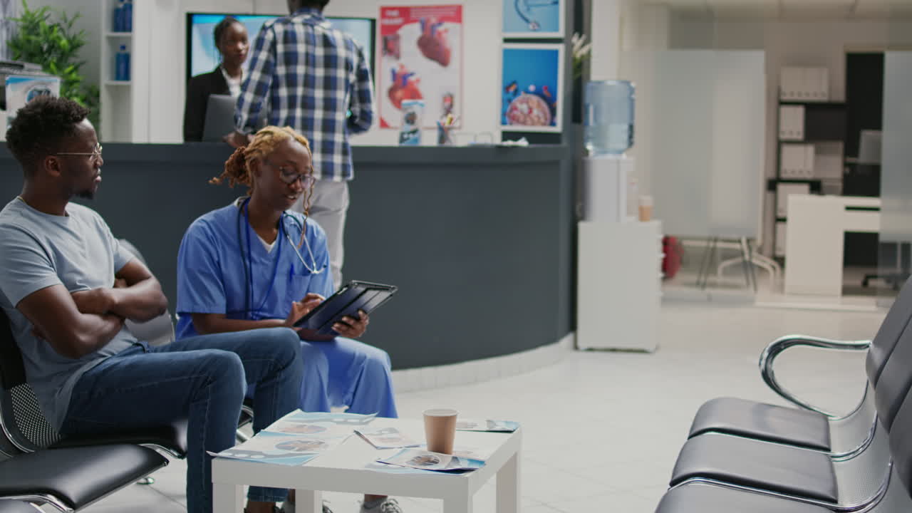 Medical assistant using digital tablet to show recovery treatment to sick adult