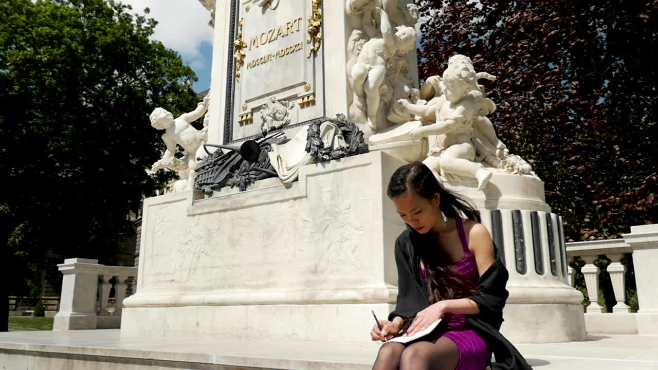 비엔나의 모차르트 기념비 앞에 앉아 있는 소녀, 글쓰기 - 슬로우 모션