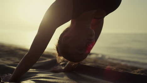 Yoga-woman-standing-downward-facing-dog-practicing-svanasana-at-sunset-close-up.