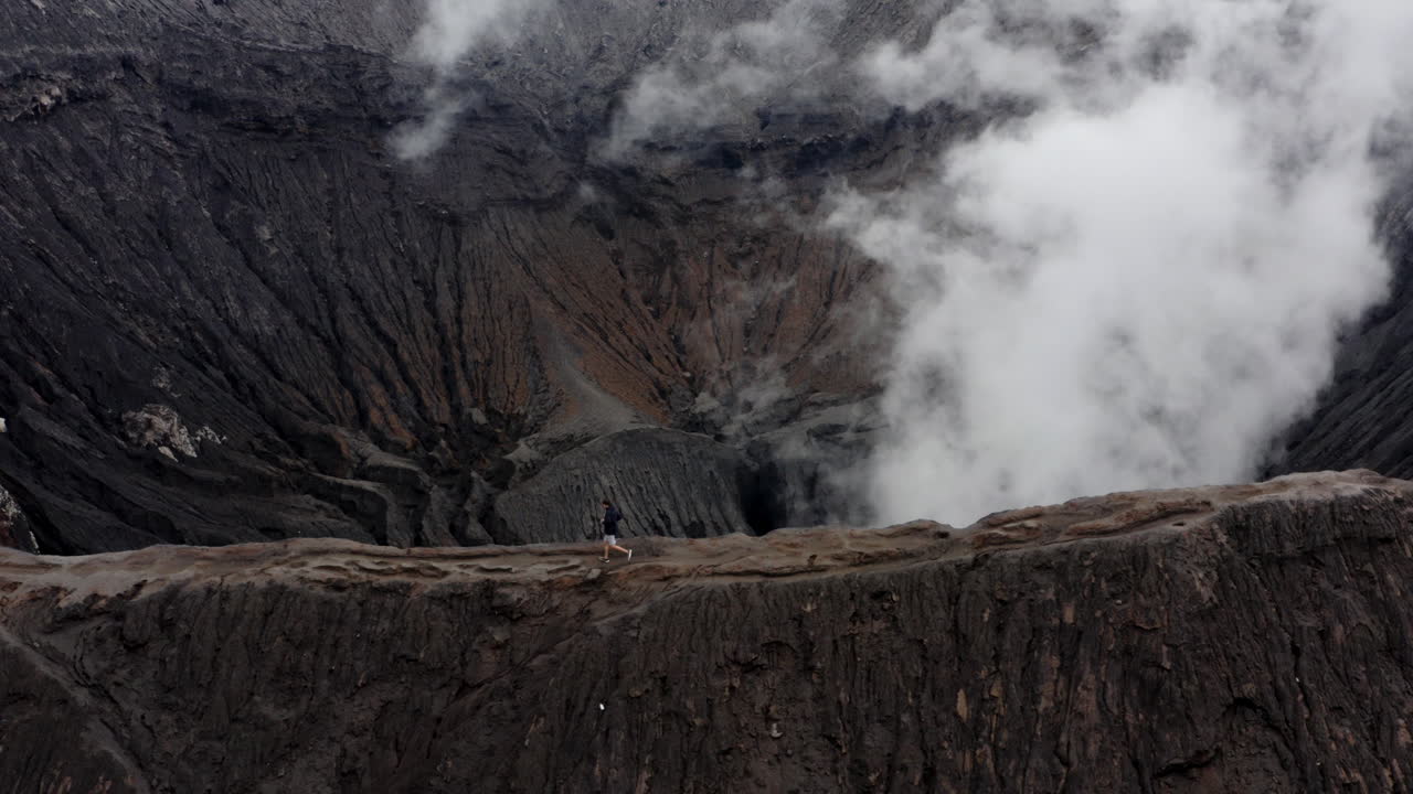 Adventurous young man running on rim of Active Mt Bromo, East Java Indonesia