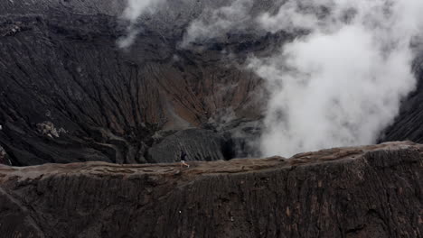 adventurous young man running on rim of active mt bromo, east java indonesia