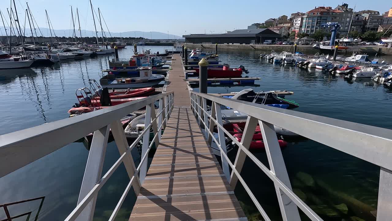 Trægangbro i havnen med søredningsbåde midt mellem fisker- og turistbåde på en behagelig solrig morgen, beskrivende optagelse.