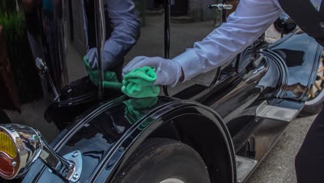 chauffeur gently polishing wheel arch of vintage car