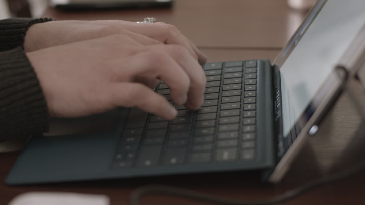 manos femeninas escribiendo en un teclado de tableta o portátil con enfoque superficial