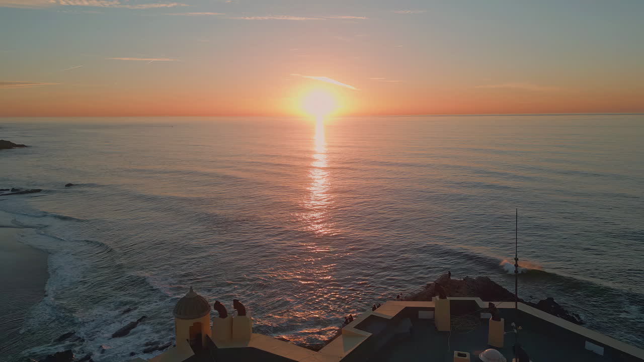 Golden sun setting down behind ocean horizon aerial view. Residential complex