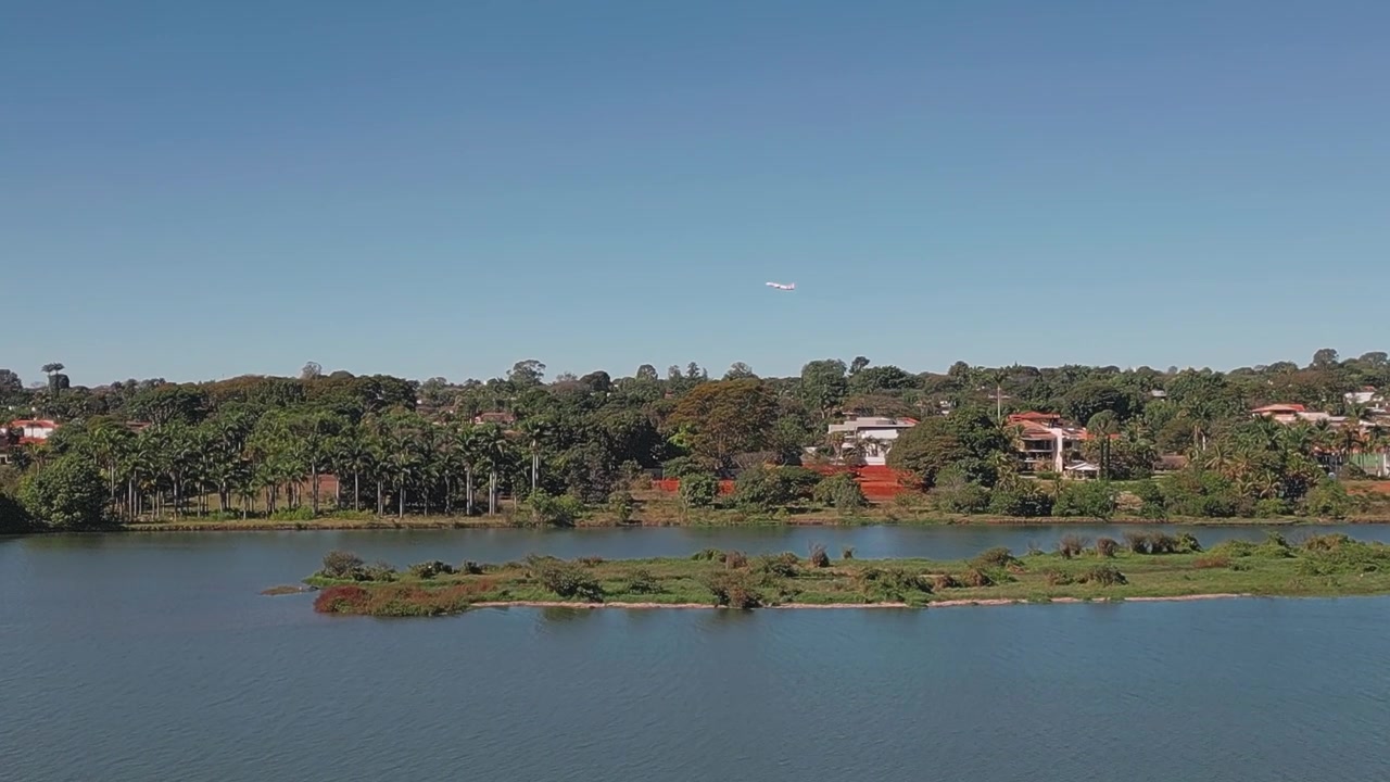 Aereo che vola sopra il Lago Paranoá a Brasilia, Distretto Federale, Brasile, rivelando il bacino d'acqua dolce, la riva alberata, il quartiere residenziale e piccole isole ricoperte di vegetazione, tracciamento con drone