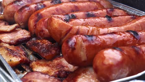 vista de cerca de tocino y salchichas de carne en la parrilla con humo