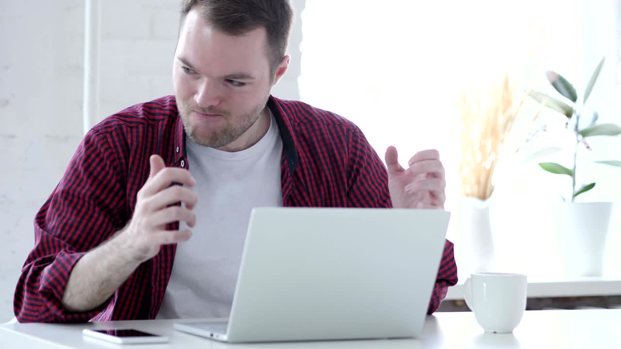 joven enojado trabajando en una computadora portátil en la oficina
