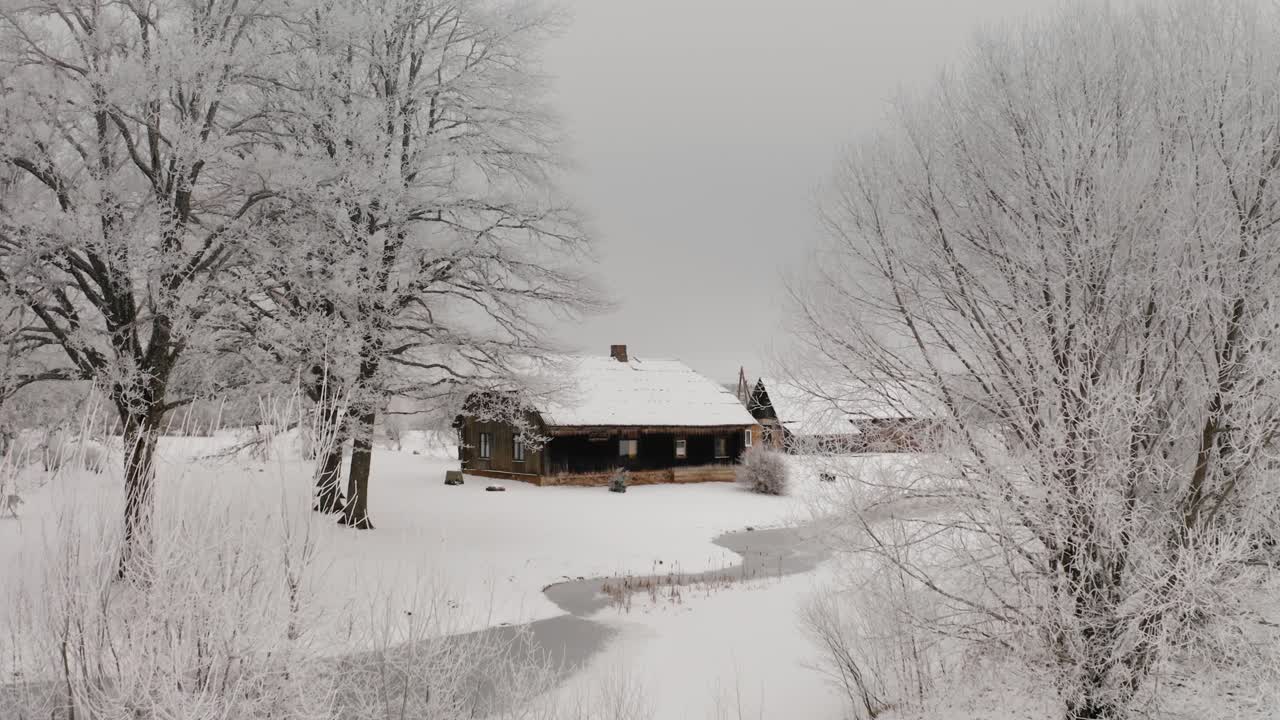 Old wooden family house in the suburbs. Winter season with snow on the ground and frozen trees. Aerial view of historic community in the countryside. Winter wonderland scenery.
