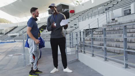 Entrenador-Masculino-Diverso-Y-Atleta-Discapacitado-Con-Pierna-Protésica-Hablando-Durante-La-Sesión-De-Entrenamiento