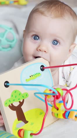 baby girl examining bright toy while laying on belly, dressed warmly and engaged in active play moment, chewing