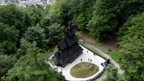 Drone-shot-descending-towards-the-Stave-church-cloudy-day-in-Fantoft,-Norway