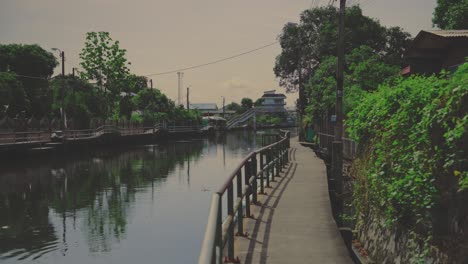 a peaceful canal-side walkway lined with greenery and railings in bangkok, thailand - static shot