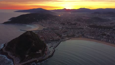 Vista-Aérea-De-La-Ciudad-De-San-Sebastián,-Playa-De-Arena-Para-Surf-Y-Paisaje-Urbano-Durante-El-Colorido-Amanecer