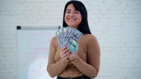 happy woman counting banknotes. attractive brunette holds many dollar bills. satisfied rich girl with a big amount of cash.