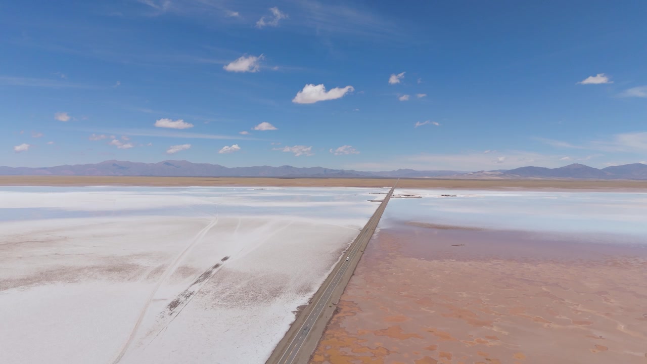 Panorama de drone das salinas de Salinas Grandes cortadas por uma rodovia reta, vista aérea.