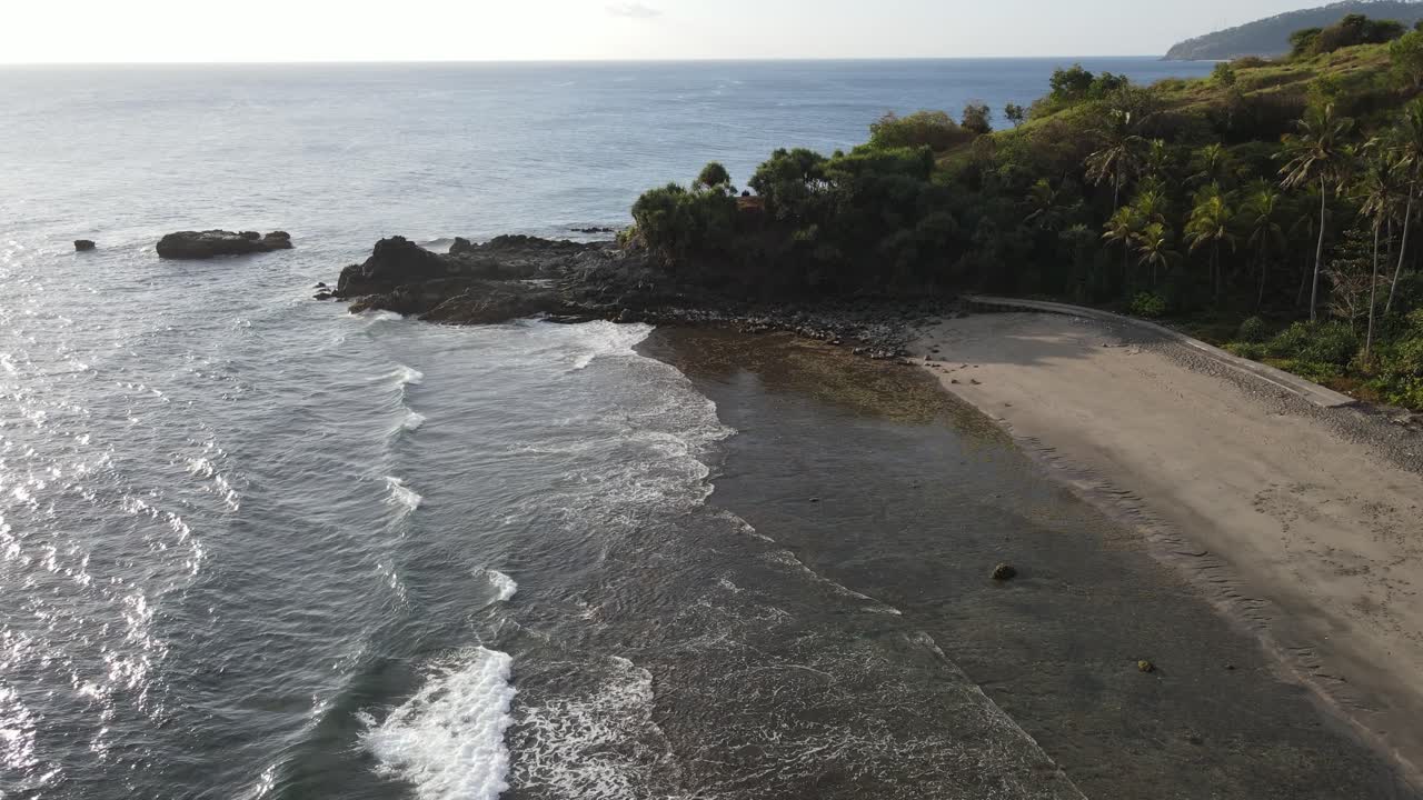 Vista aérea de playa tropical con suaves olas oceánicas y costa exuberante