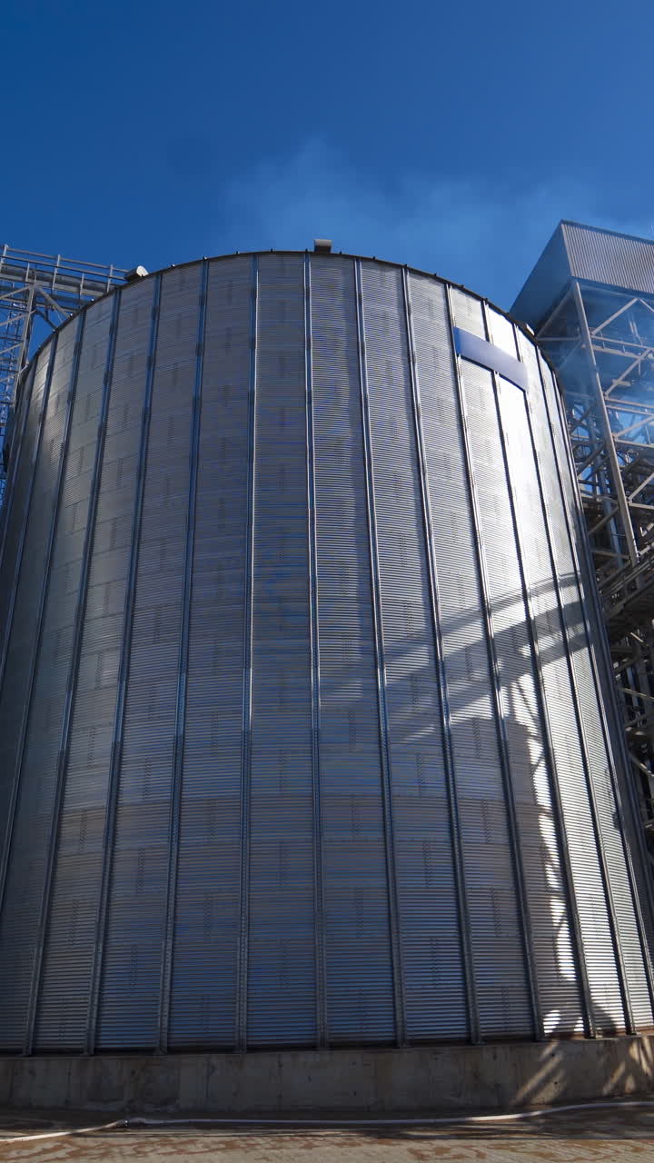 Exterior of grain elevators on field. Large granary of a modern industrial plant for agriculture. Industrial complex for storage crop. Vertical video