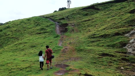 father and daughter walking up a hill in batanes, philippines - pan up