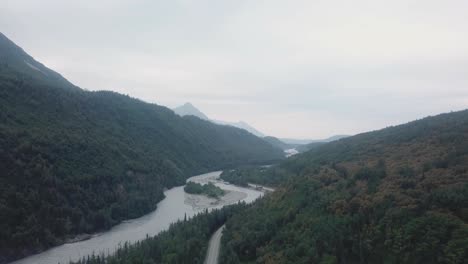aerial view, drone flight along the glenn highway and the matanuska river in the chugach mountain range of central alaska on a cloudy summer day