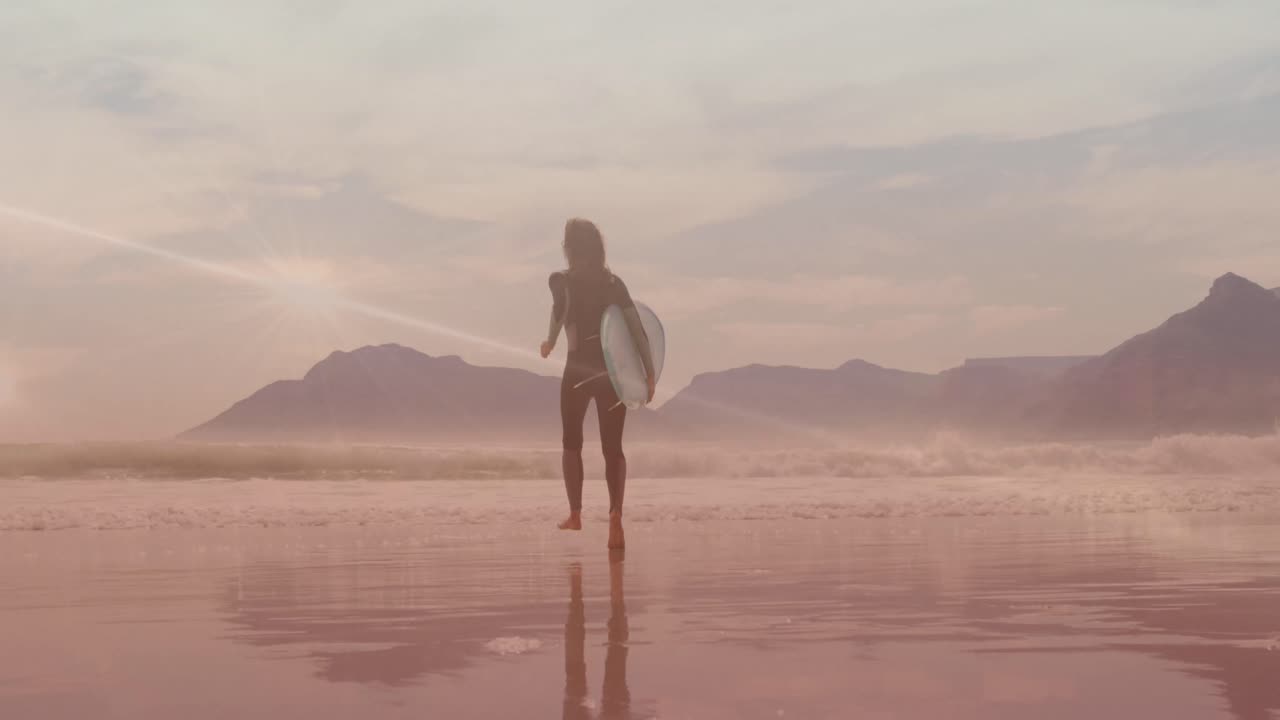 Animation af lysspor over kaukasisk kvinde der går med surfbræt på stranden