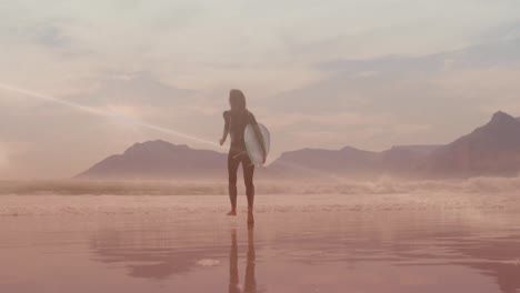 Animation-Von-Lichtspuren-über-Einer-Kaukasischen-Frau,-Die-Mit-Einem-Surfbrett-Am-Strand-Spaziert