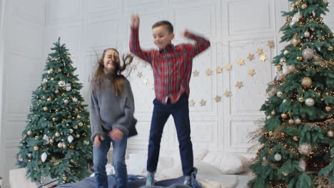 niños divertidos teniendo una fiesta de salto en una cama doble. niña sonriente cayendo en una cama grande