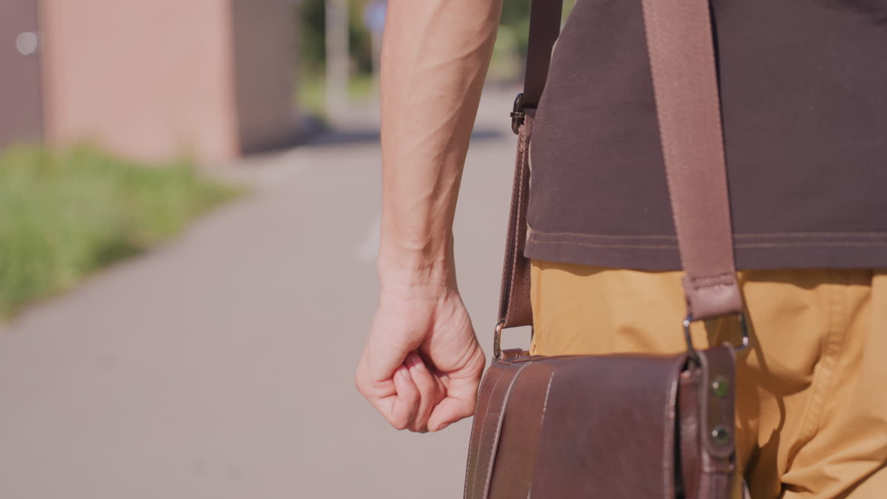 Close View Of Hand And Strap Movement, Detailed Image Capturing Hand Securing Leather Handle During Walk, Photograph Showing Hand Gripping Strap As Someone Strolls On Sunlit Pavement