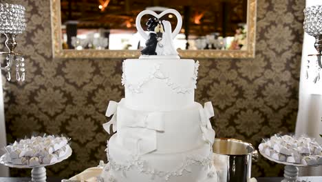 Captura-Detallada-En-Camión-De-Un-Delicioso-Pastel-De-Bodas,-Con-Un-Lindo-Adorno-De-Pastel-Hecho-A-Mano-Para-Los-Novios-Sobre-Una-Mesa-De-Dulces-Decorada