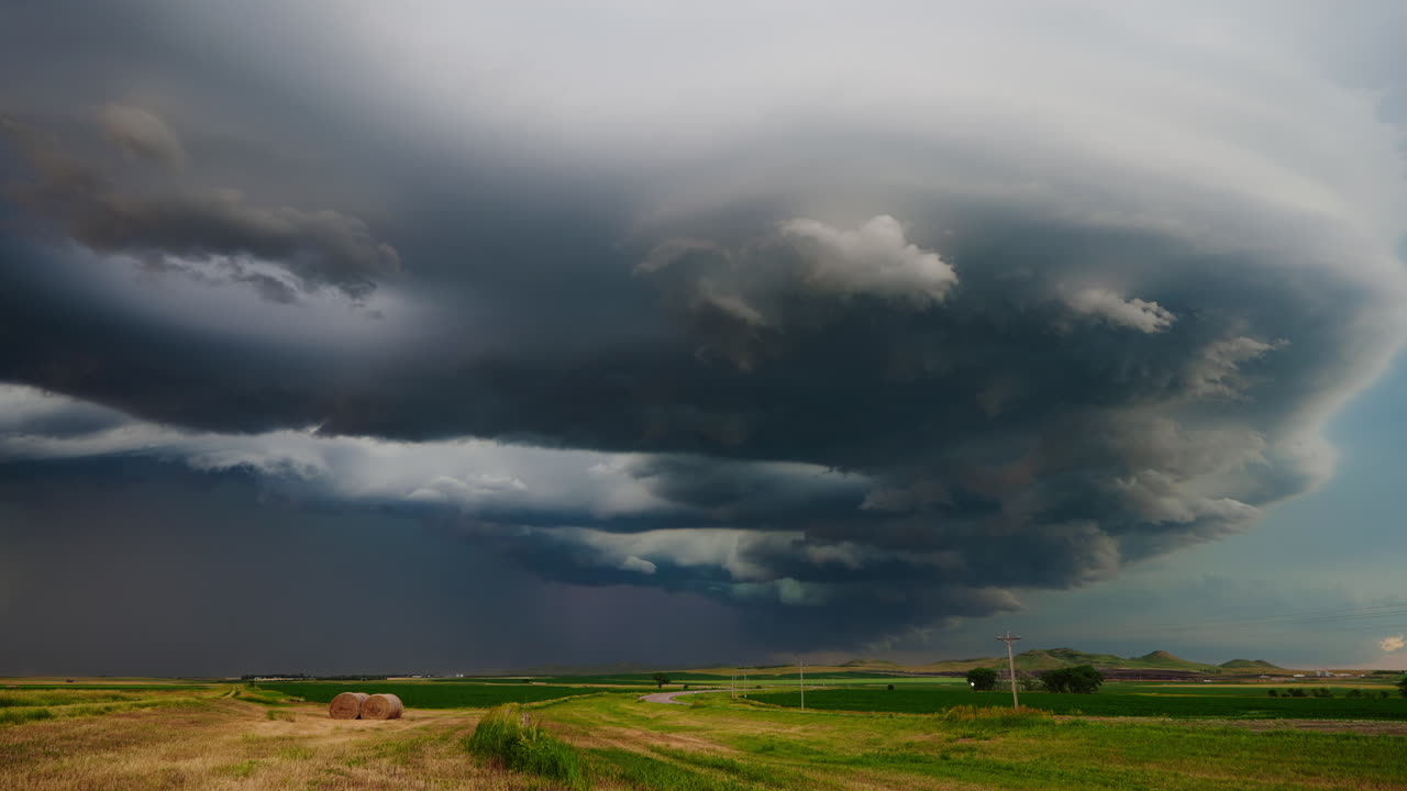 Dramatic supercell storm cloud over a rural landscape