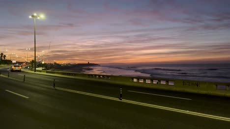 static view of a road with cars passing by the sea. night