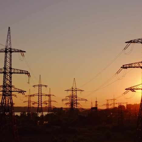 high-voltage power towers. the dark silhouette of towers in the rays of the beautiful evening sun. electric pylons at dusk. global warming.
