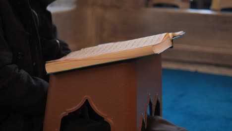 a muslim man reading the quran in a mosque