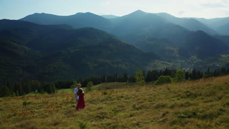 ein junges paar tanzt an einem sonnigen tag gegen ein atemberaubendes bergpanorama.