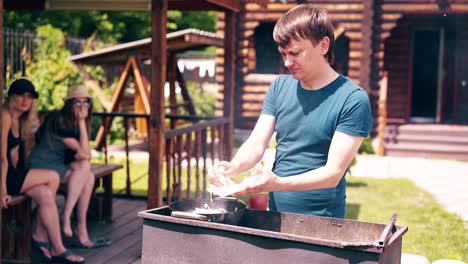 Young-man-makes-pilaf-in-a-cauldron-on-a-grill-on-an-open-fire-Adds-the-onion