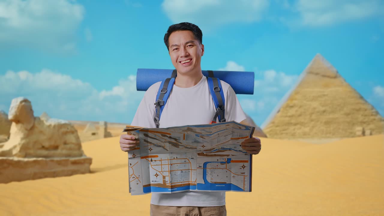 Asian Male Hiker With Mountaineering Backpack Looking At The Map Then Smiling To Camera While Traveling In Pyramid Of Giza