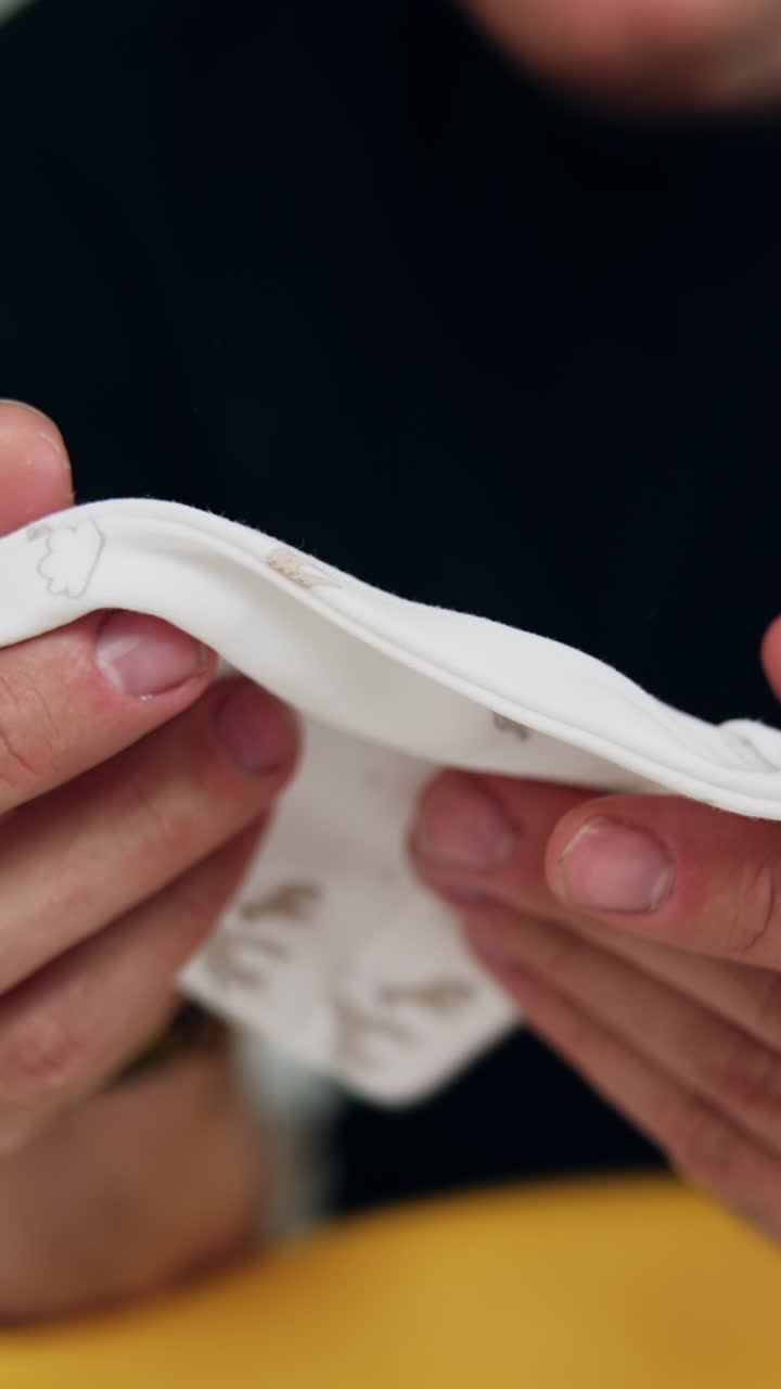 Hands of unrecognized man hold the tiny baby cap. Future father expecting for his newborn. Close up. Vertical video