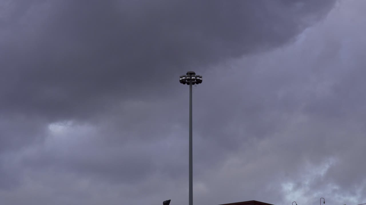 cámara lenta: la tormenta se acerca, un poste de luz en el medio del cuadro está temblando por el intenso viento