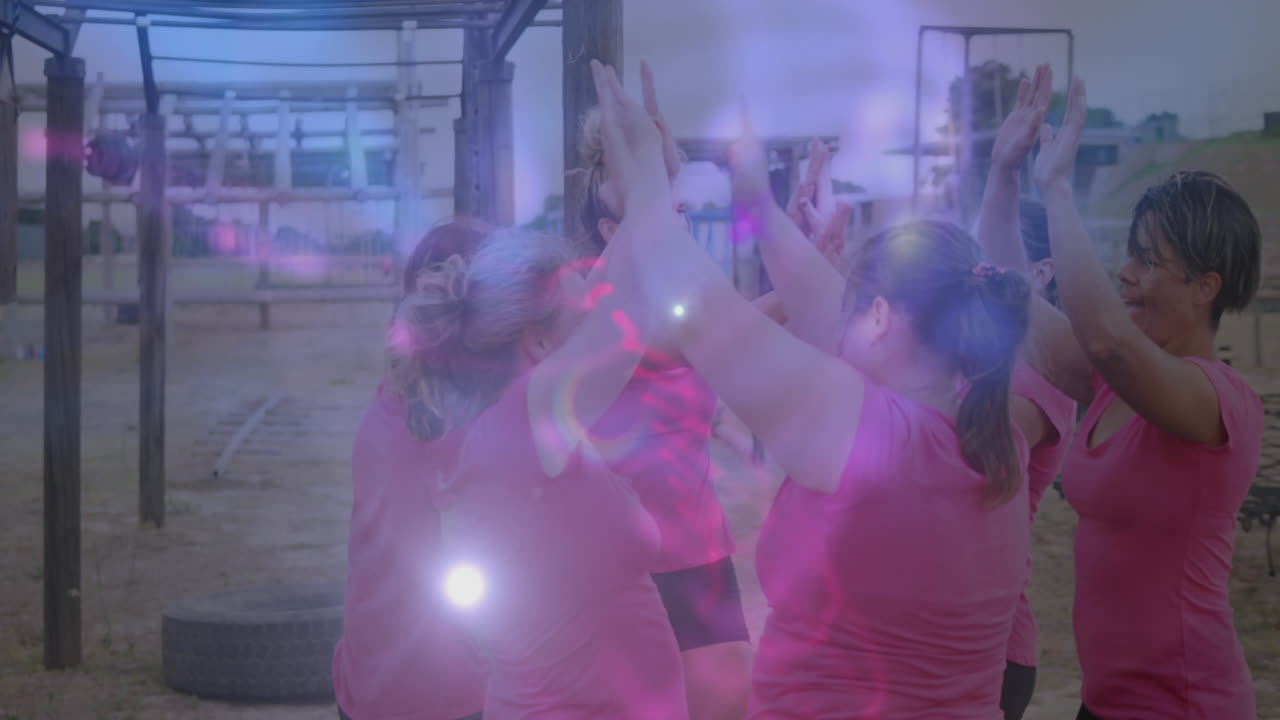 Animation of light spots over diverse women at obstacle course high fiving