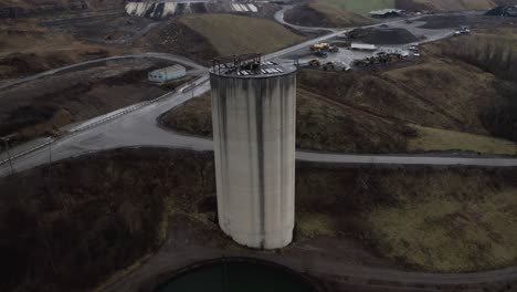 drone orbit shot around a waste tower with a flock of birds flying toward to the camera