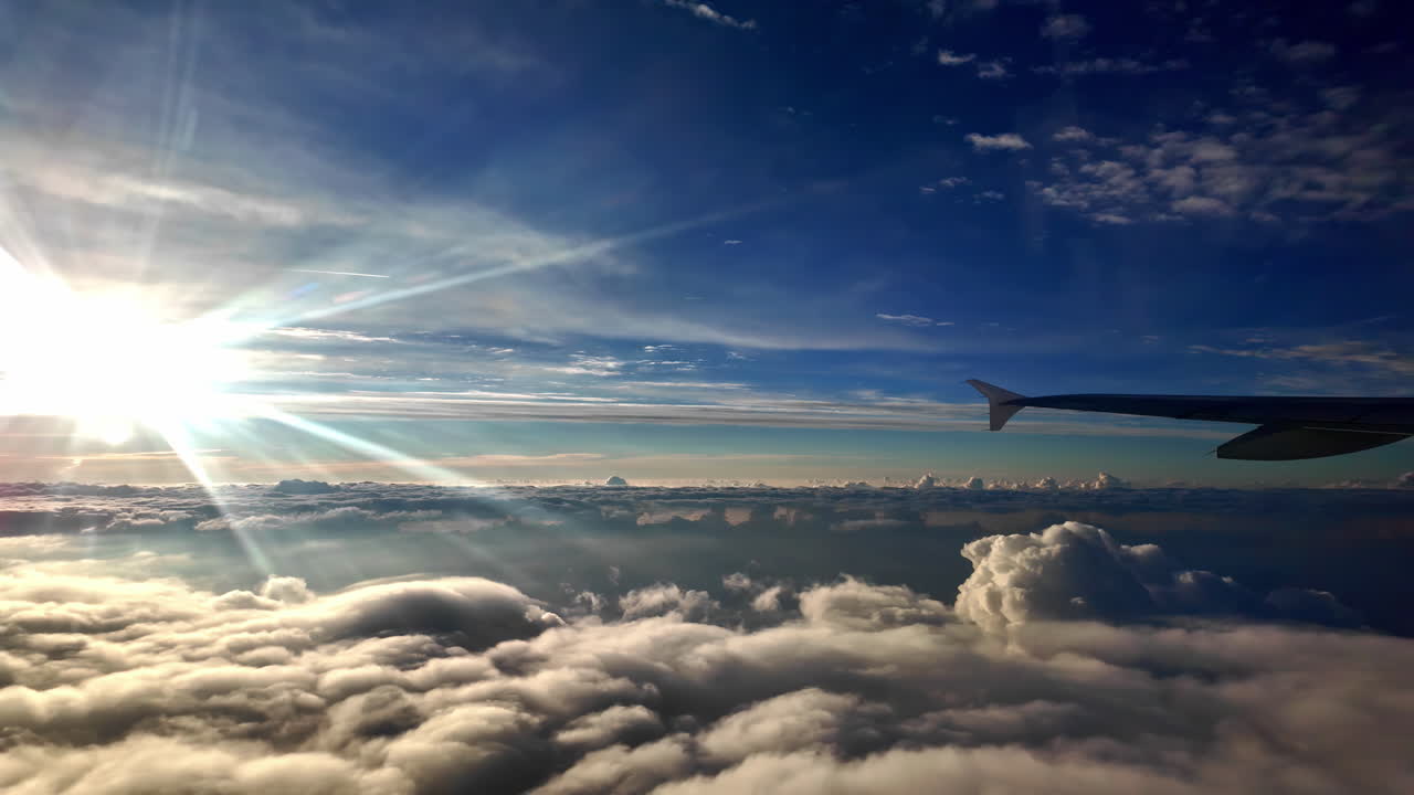 A Silhouette of a Plane Soaring Above Sunlit Cloud Beds - Pan Right Shot