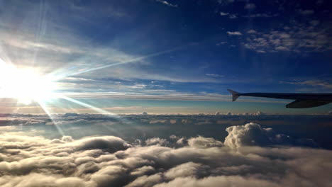 a silhouette of a plane soaring above sunlit cloud beds - pan right shot
