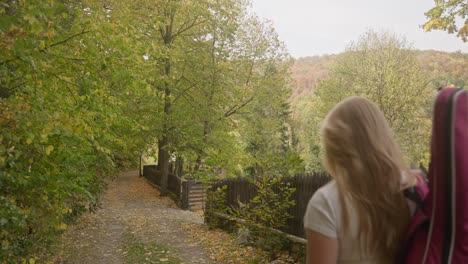 Happy-female-musician-walks-autumn-leafy-forest-lane-Bulgarian-village