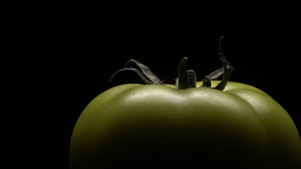 검은 바탕에 회전하는 초록색 토마토.