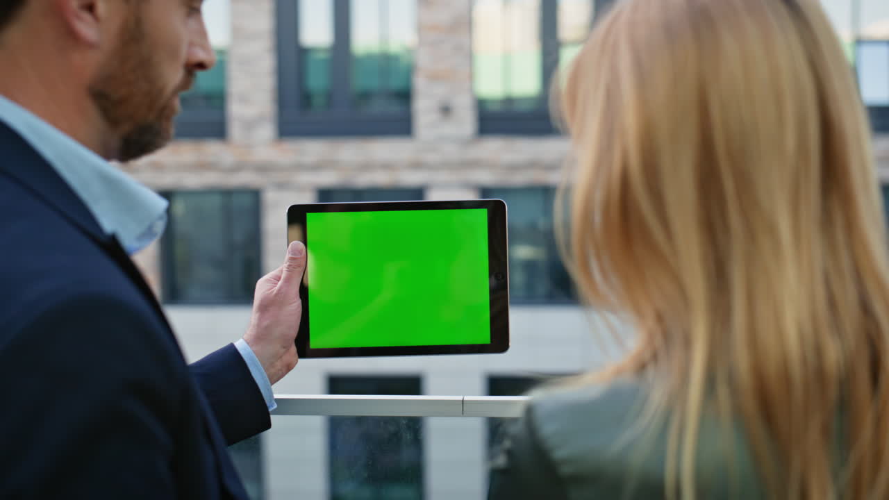 Business couple looking greenscreen tablet standing at urban district closeup