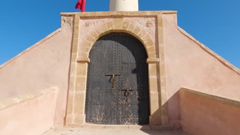Leuchtturm-Von-Rabat-Und-Angrenzender-Turm-Mit-Leuchtend-Roter-Flagge-Vor-Blauem-Himmel---Marokko