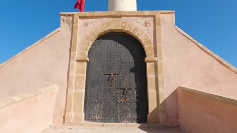 rabat lighthouse and adjacent tower with vibrant red flag against blue sky - morocco