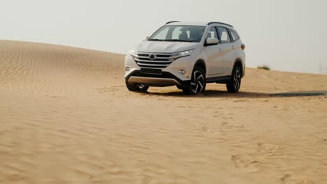 white suv driving through sand dunes