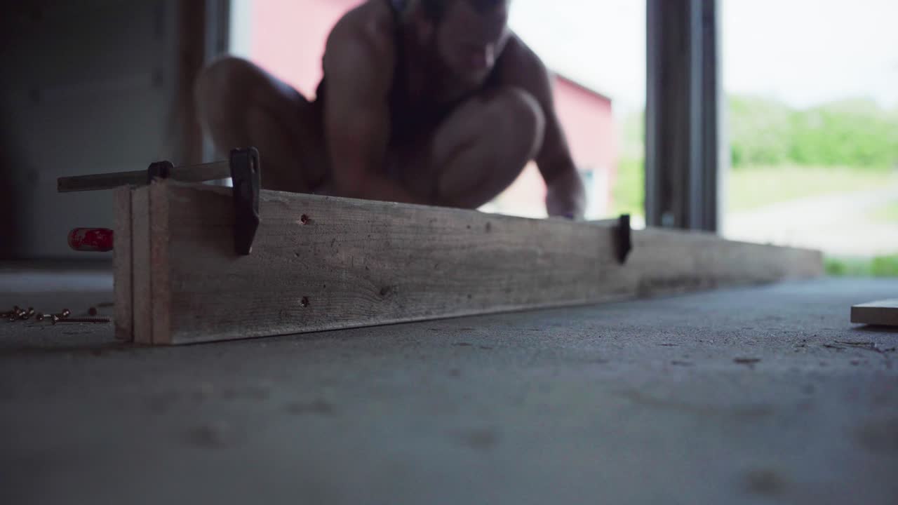 Falegname che usa i morsetti su una tavola di legno in officina.