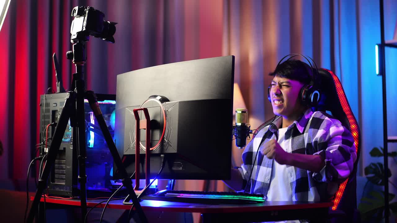 asian boy streamer gritando gol y bailando celebrando el juego ganador a través de la red en la computadora personal. videojuego de transmisión en vivo, escritorio iluminado por luz de tira led rgb
